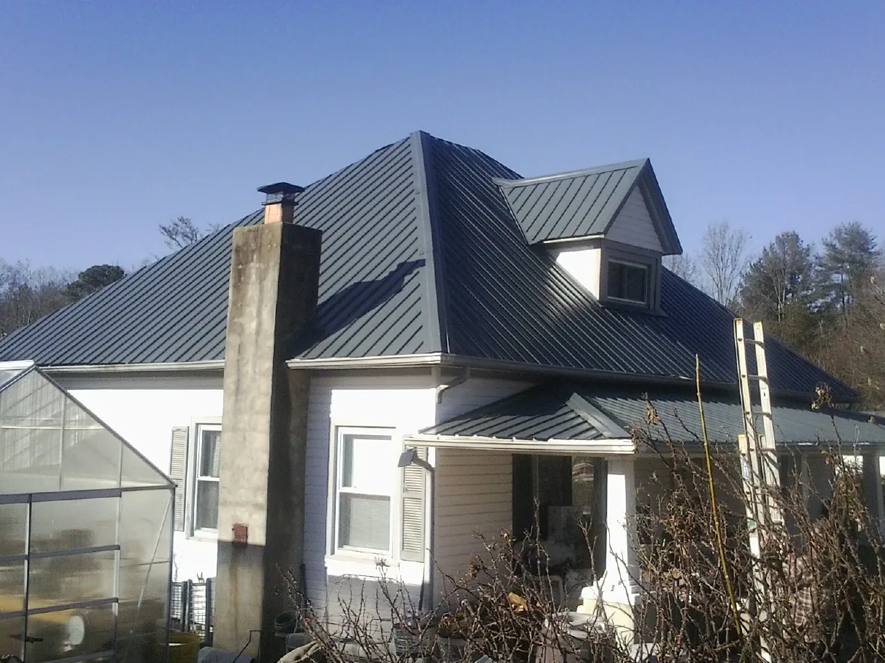 Dark blue standing seam metal roof on a white farmhouse with dormer — Slate & Tile Roof Repair by Roofing Brothers in Adairsville