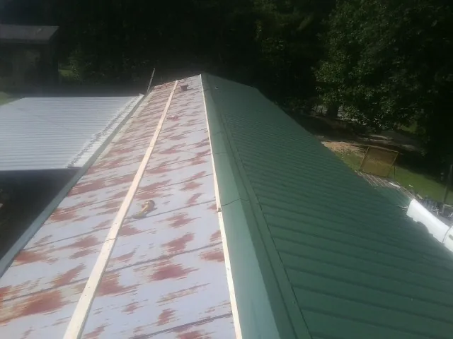 Old rusted panels beside newly installed green metal roofing — Wind Damage Roof Repair by Roofing Brothers in Adairsville