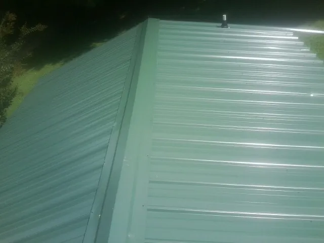 New green metal panels meeting at the ridge of a roof — Flat Roof Repair work by our crew in Adairsville