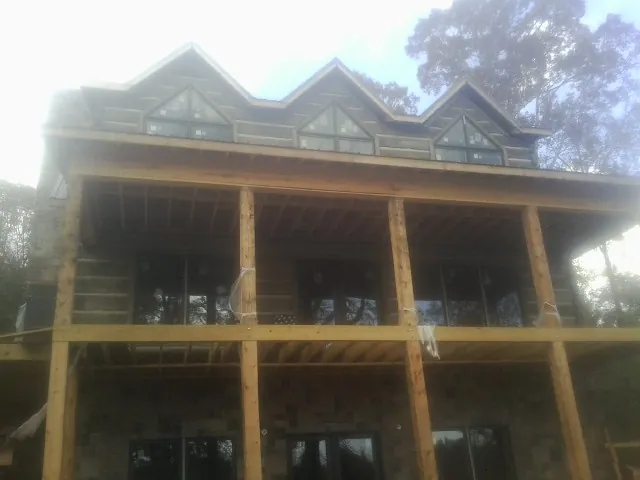 Dormers and porch framing on a large log home under construction — Roof Coating work by our crew in Adairsville