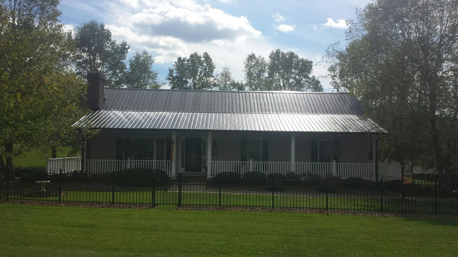 Gray metal roof on a brick ranch with a full width front porch — Gutter Guard Installation work by our crew in Adairsville