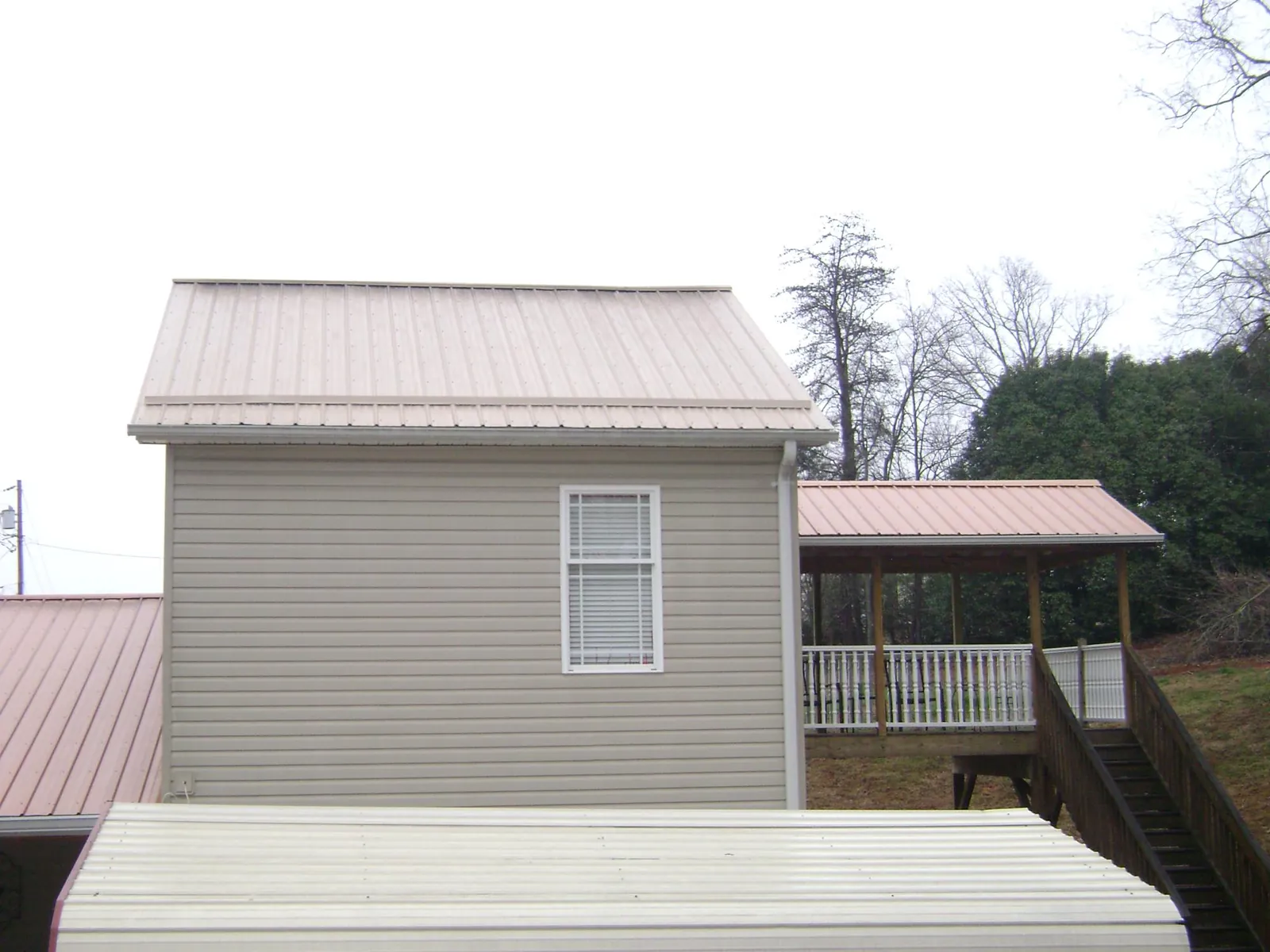 Tan metal roofs on a two story addition and attached porch, from a Roof Replacement job in Adairsville