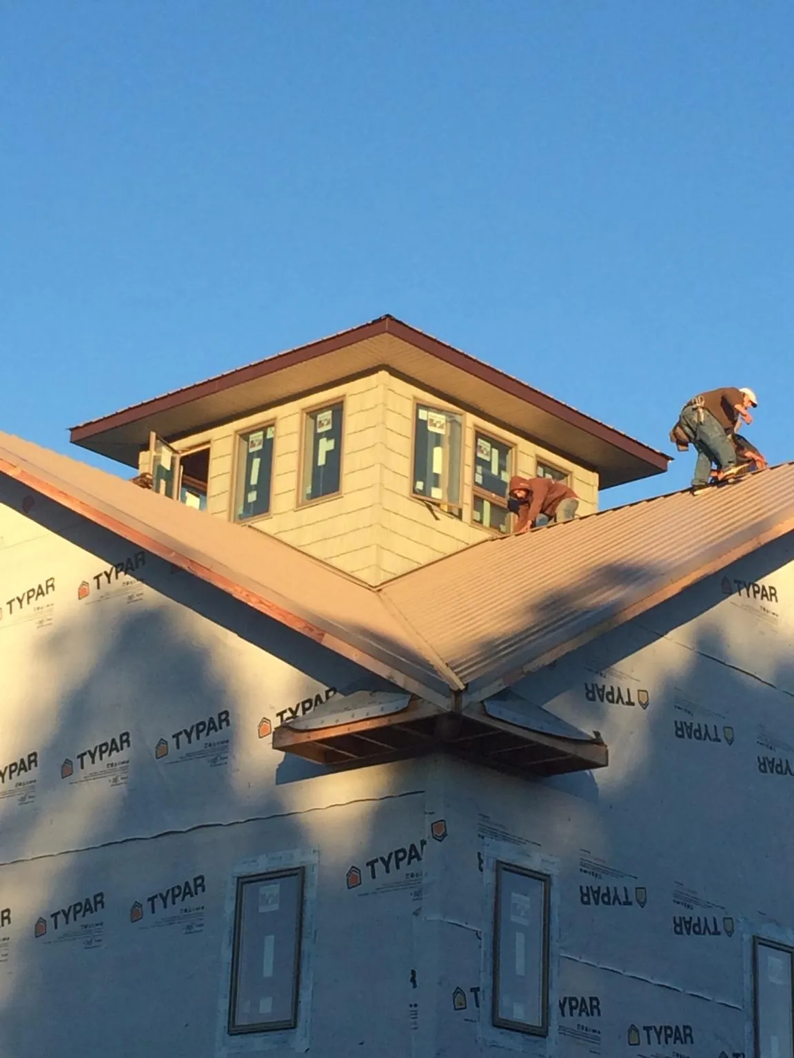 Roofers working around a rooftop cupola on a new metal roof at sunset — Roof Waterproofing in Adairsville by Roofing Brothers